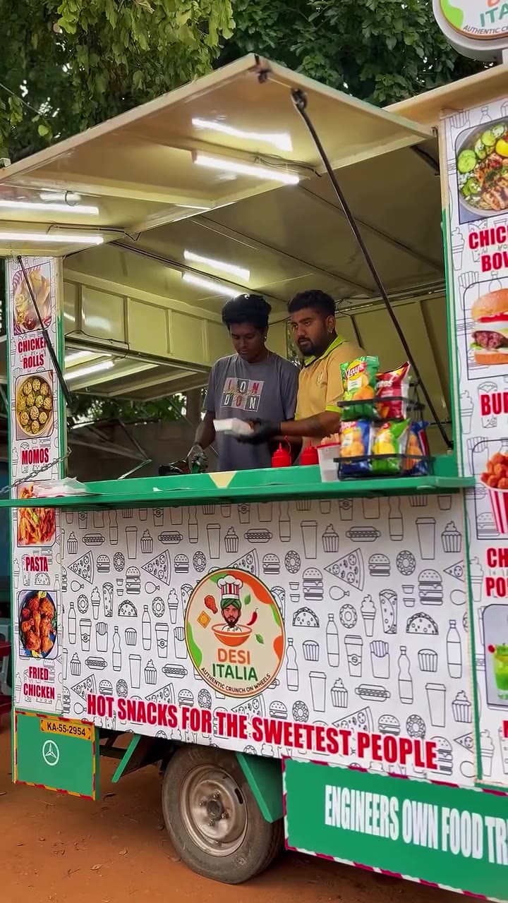 The DESI ITALIA food truck at dusk with its serving window open, white doodle wrap and green trim